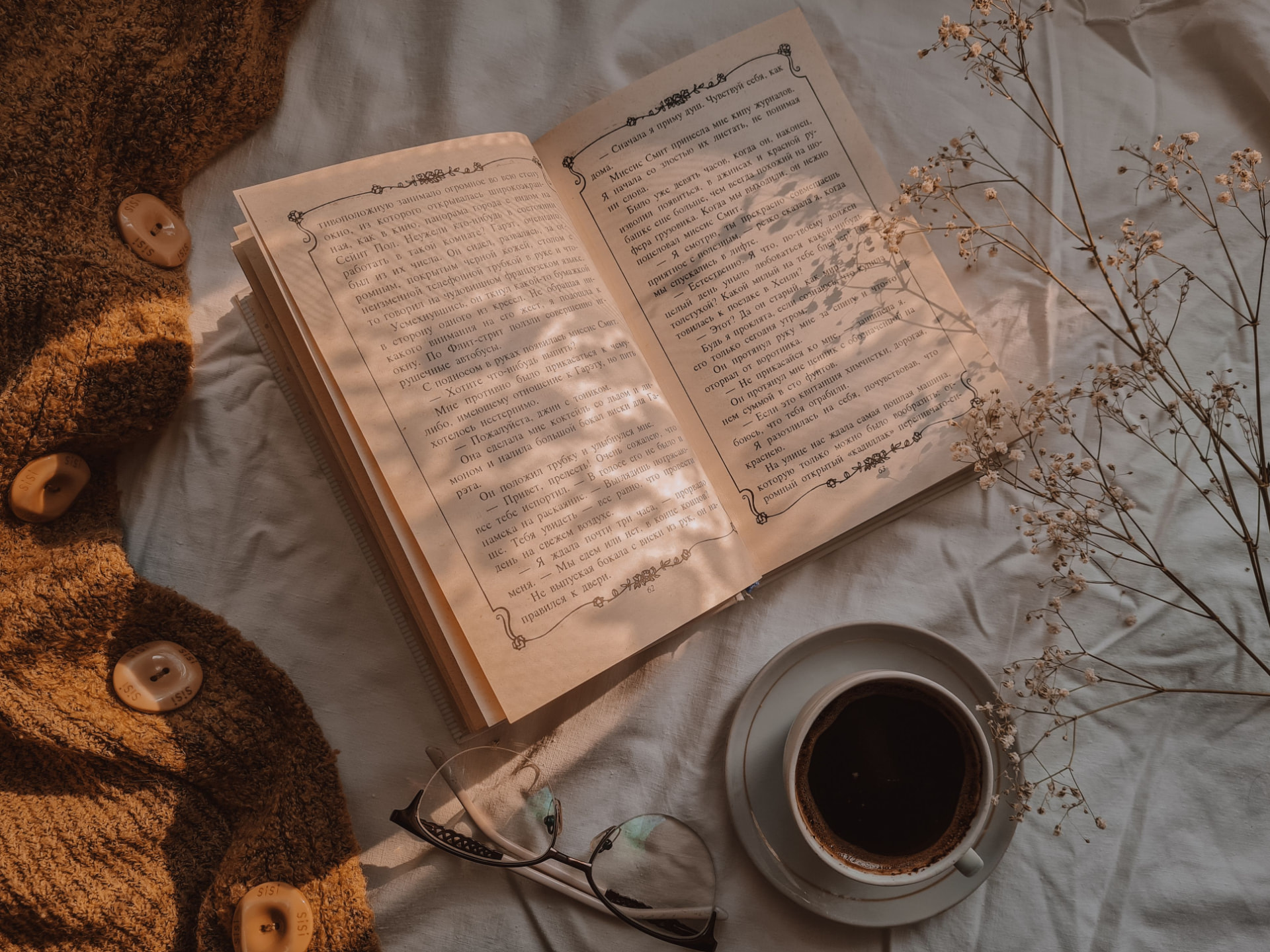 An open book, reading glasses and coffee in warm afternoon light
