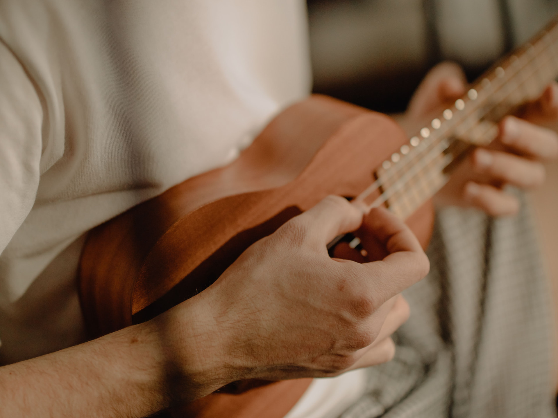 A person playing a small wooden stringed instrument